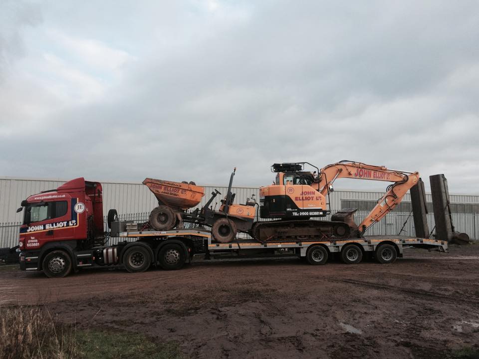 Red low loader carrying a dumper and an excavator