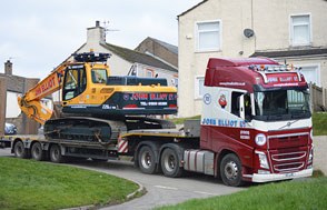 Red Volvo low loader lettered John Elliot Ltd with an excavator on board