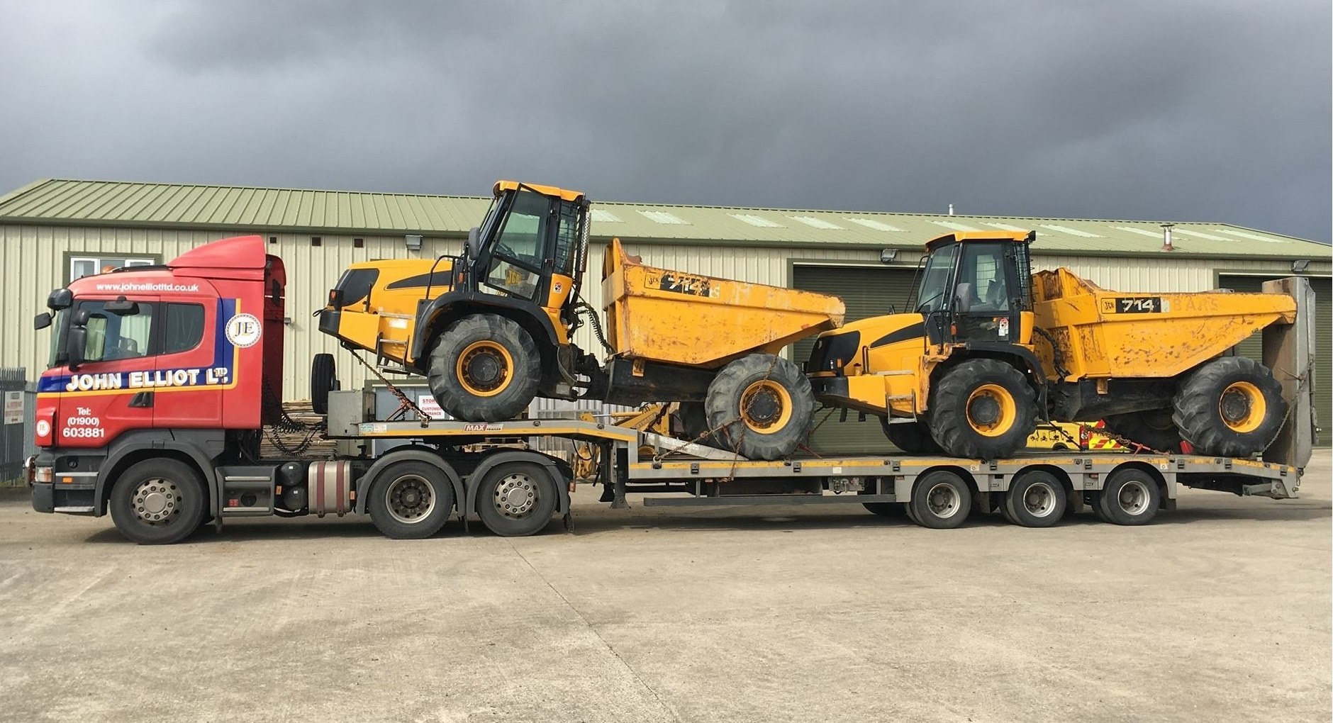 Low loader in John Elliot livery carrying two yellow JCB dump trucks